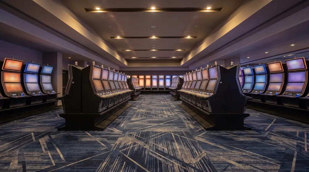 Generated image: an empty slot floor in the early morning, long curved rows of machines with plain colour screens under recessed ceiling lights; not a photograph of the casino.